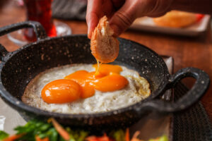 Dipping Bread into Sunny Side Up Eggs